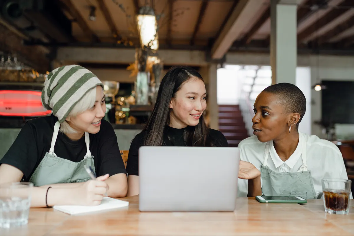 Three people discussing ideas around a laptop